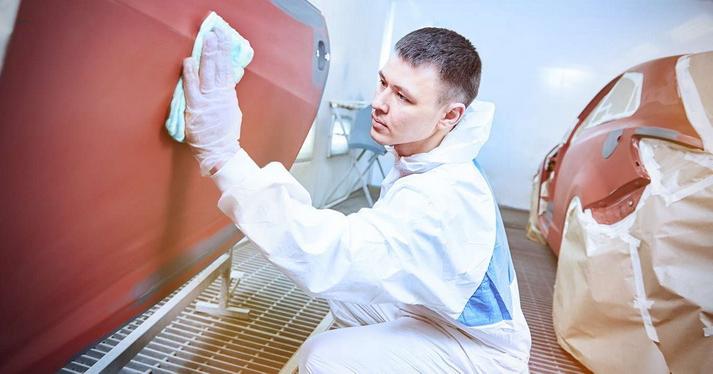 man in a white plastic suit wiping machine